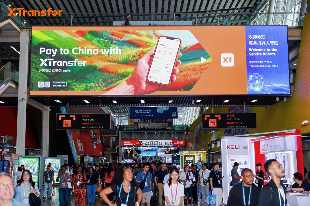 XTransfer billboard inside Canton Fair exhibition hall with visitors on the show floor
